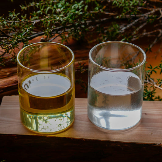 Two open glass containers showcasing the unique properties of Mānuka Oil and Mānuka Hydrosol, set against a natural background